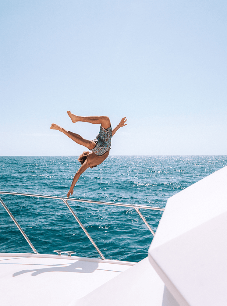 Man jumping over the side of a yacht into the ocean